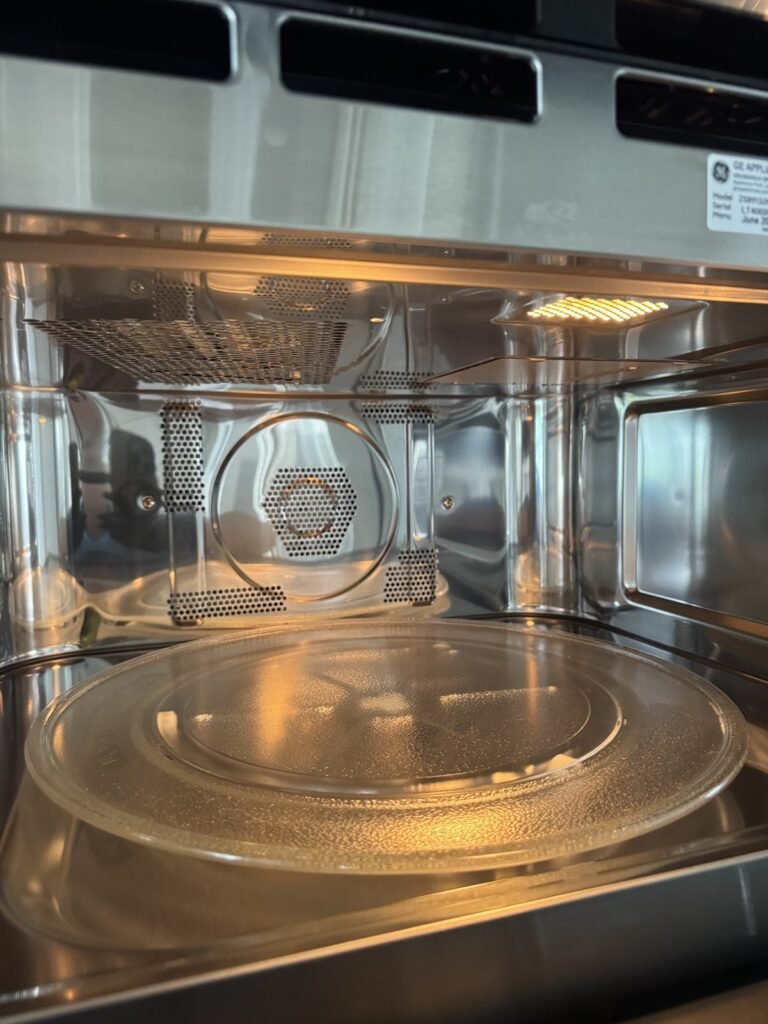 Clean glass microwave tray back in a polished stainless cavity after JenyClean deep cleaning in Bellevue, WA