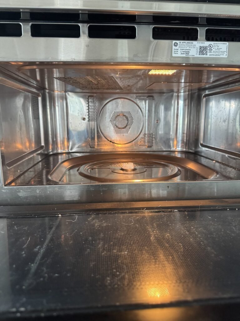 Stainless microwave cavity with splatter and a smeared inner door panel before JenyClean deep cleaning in Bellevue, WA