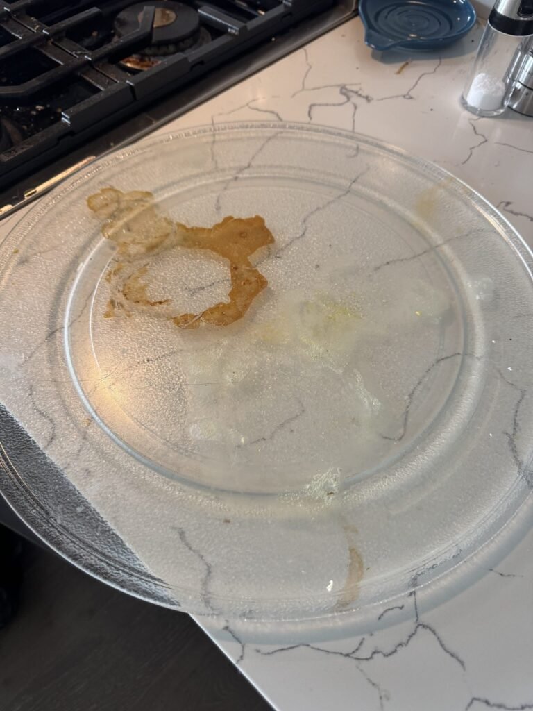 Microwave glass tray with a dried brown sauce ring before JenyClean kitchen deep cleaning in Bellevue, WA