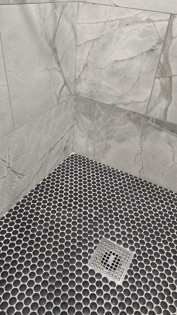 Black penny mosaic shower floor with clean light gray grout and polished tile after JenyClean deep cleaning in Bellevue, WA
