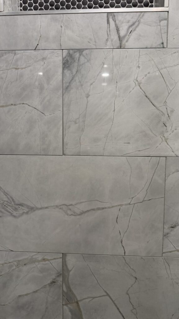 Marble-look shower wall tile with clean light grout lines and glossy finish after JenyClean deep cleaning in Bellevue, WA
