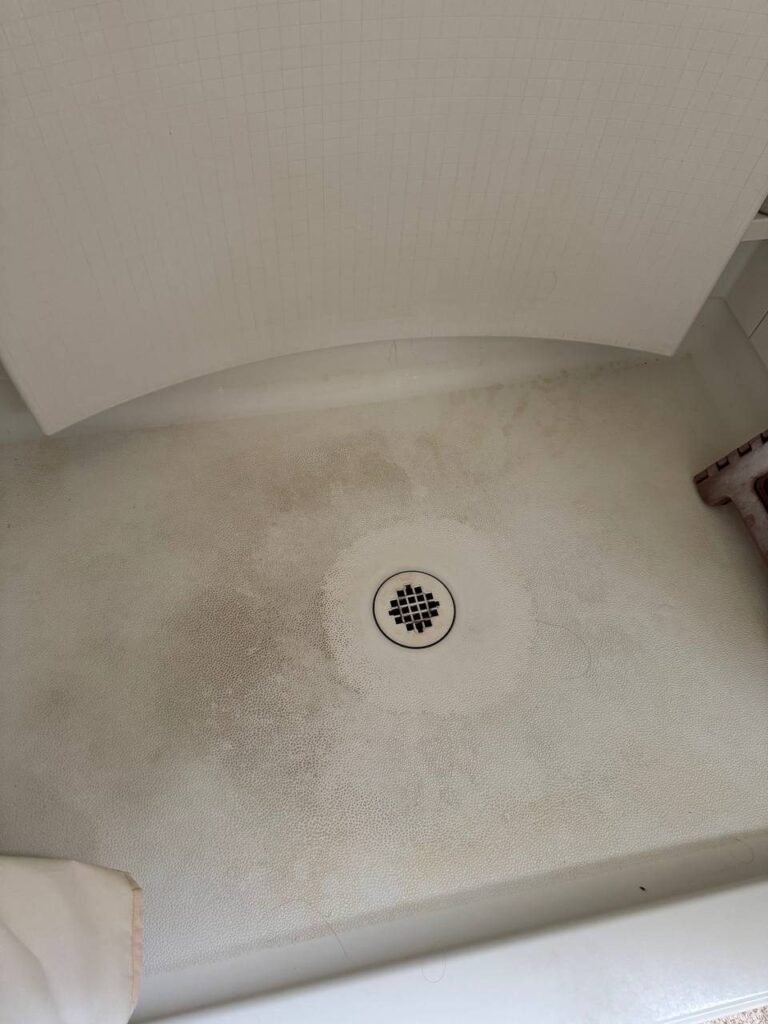 Textured shower pan with tan film and mildew in the corners before JenyClean deep cleaning in Bothell, WA