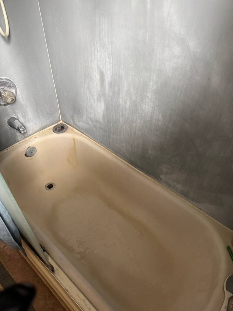 Cream enamel bathtub with rust streak, gray film and bath mat marks before JenyClean bathroom deep cleaning in Bothell, WA