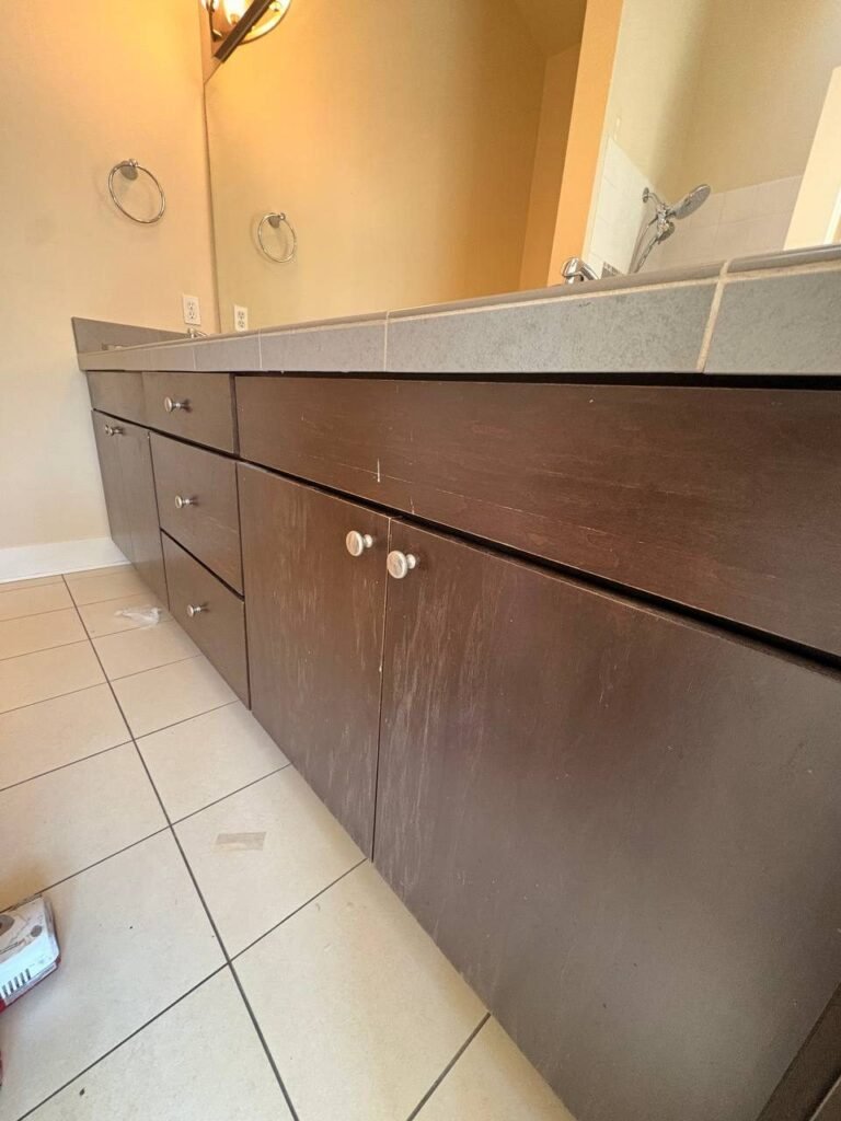 Dark bathroom vanity fronts streaked with pale dust after a remodel, before JenyClean deep cleaning in Issaquah, WA
