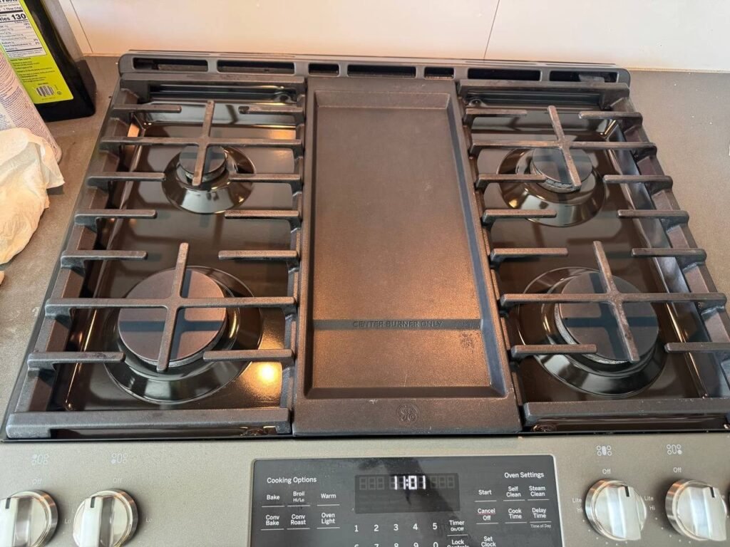 Clean gas cooktop with glossy black burner pans and grates set back in place after JenyClean deep cleaning in Issaquah, WA