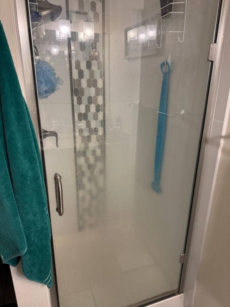 Clear glass shower door clouded with white mineral scale before JenyClean deep cleaning in Issaquah, WA