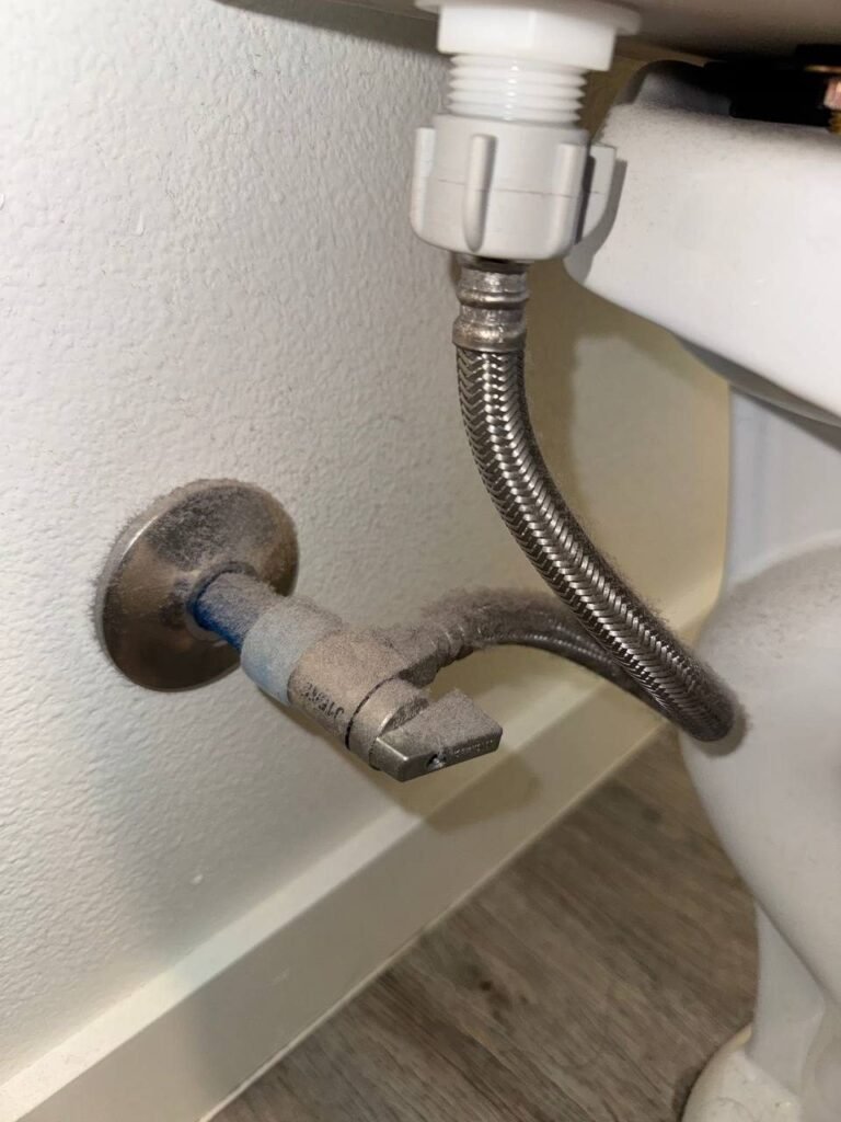 Toilet water supply line, shutoff valve and wall plate coated in thick gray dust before JenyClean deep cleaning in Issaquah, WA