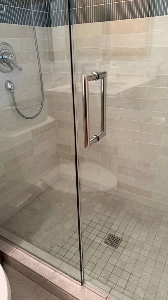 Clear frameless glass shower door and clean tile after JenyClean deep cleaning in Kirkland, WA