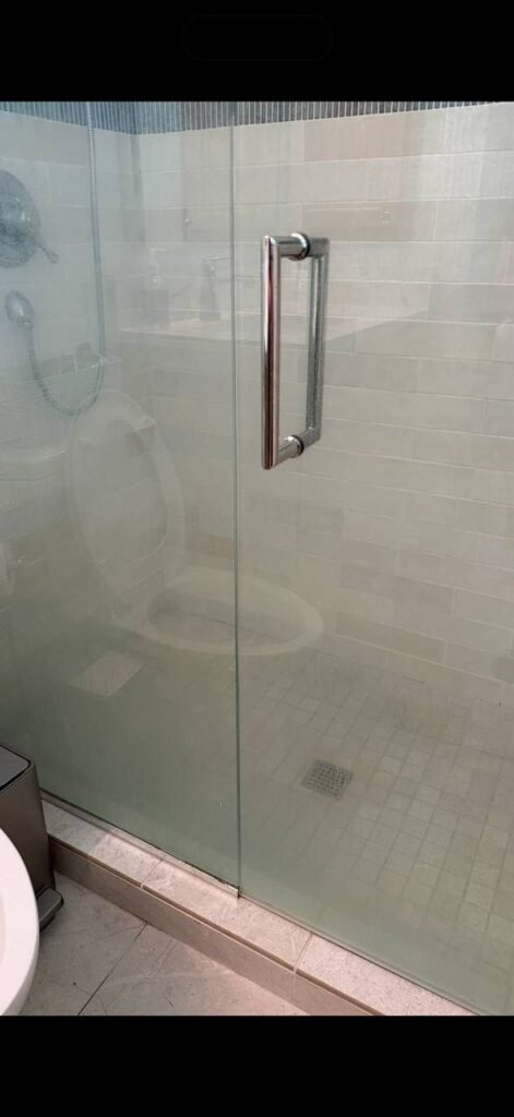 Glass shower door clouded with white water spots before JenyClean deep cleaning in Kirkland, WA
