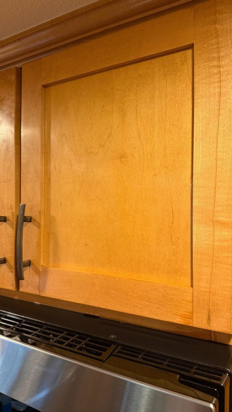 Clean wood cabinet door with an even finish above the microwave after JenyClean kitchen deep cleaning in Kirkland, WA