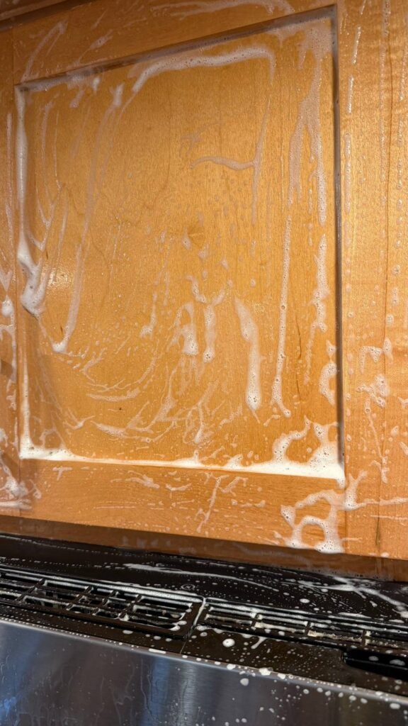 Wood-safe foam cleaner on a kitchen cabinet door above the microwave during JenyClean deep cleaning in Kirkland, WA