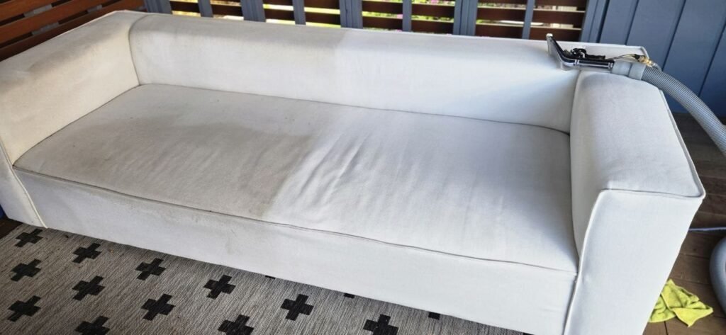 Upholstery extraction wand and hose on a patio sofa mid-cleaning by JenyClean in Kirkland, WA
