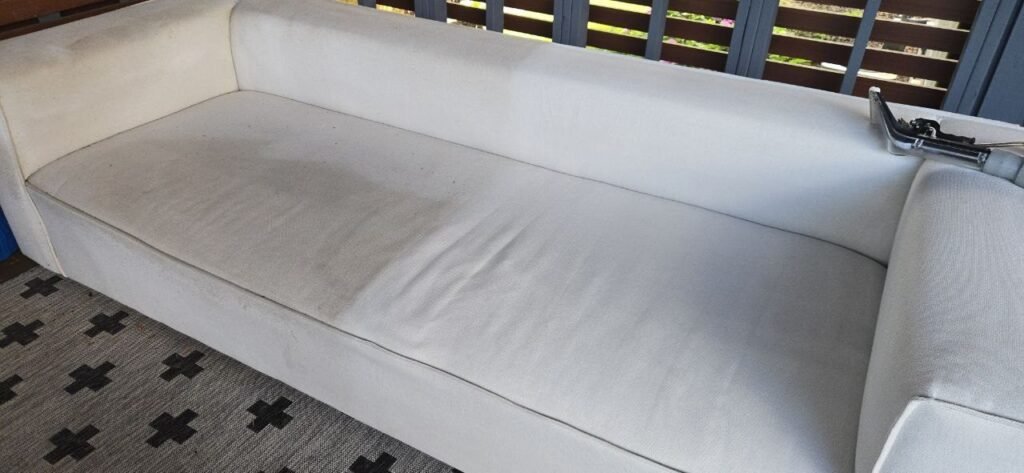 Patio sofa seat with a gray soiled half and a clean white half during JenyClean upholstery cleaning in Kirkland, WA