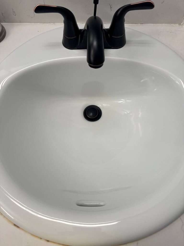 Black faucet with even dark finish over a clean white sink after JenyClean bathroom deep cleaning in Redmond, WA