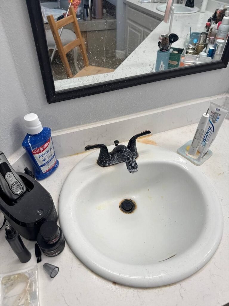 Black bathroom faucet covered in white mineral scale with stained sink basin before JenyClean bathroom deep cleaning in Redmond, WA