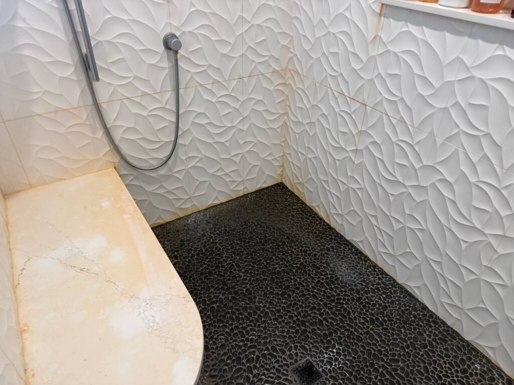 White textured shower tile with pink film along the grout lines before JenyClean deep cleaning in Redmond, WA