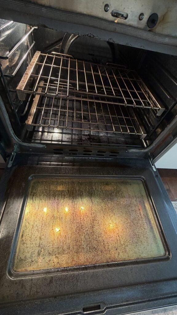 Oven with brown grease film on the inner door glass and carbon on the floor before JenyClean deep cleaning in Redmond, WA