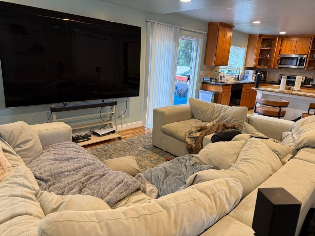 Sectional sofa with scattered throws and cushions in a Redmond, WA living room before JenyClean monthly cleaning