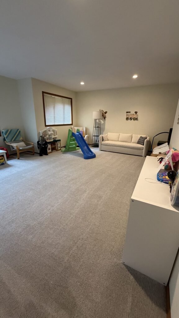 Organized basement playroom with open vacuumed carpet and toys stored on the cabinet after JenyClean cleaning in Sammamish, WA
