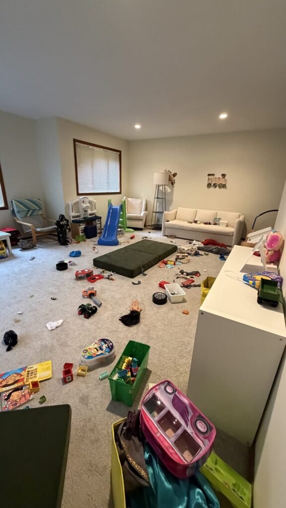 Basement playroom with toys, building bricks and an open play mattress across the carpet before JenyClean cleaning and organizing in Sammamish, WA