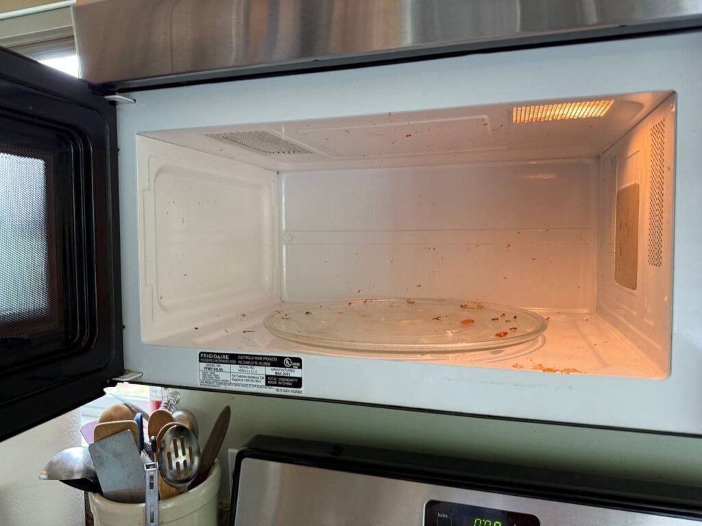 Microwave interior with food splatter on walls and turntable before JenyClean kitchen cleaning in Seattle, WA