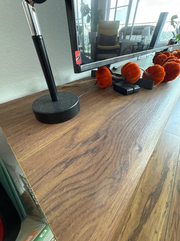 Loose dog hair scattered across a wooden TV console top before JenyClean deep cleaning in Seattle, WA