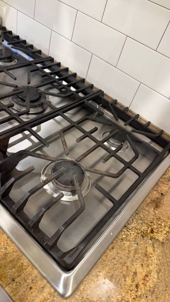 Clean stainless gas cooktop with grates in place after JenyClean detailed cleaning in Seattle, WA