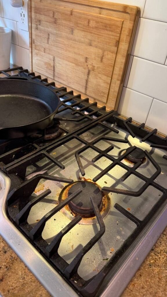 Gas cooktop with grease rings around the burners and crumbs before JenyClean detailed cleaning in Seattle, WA