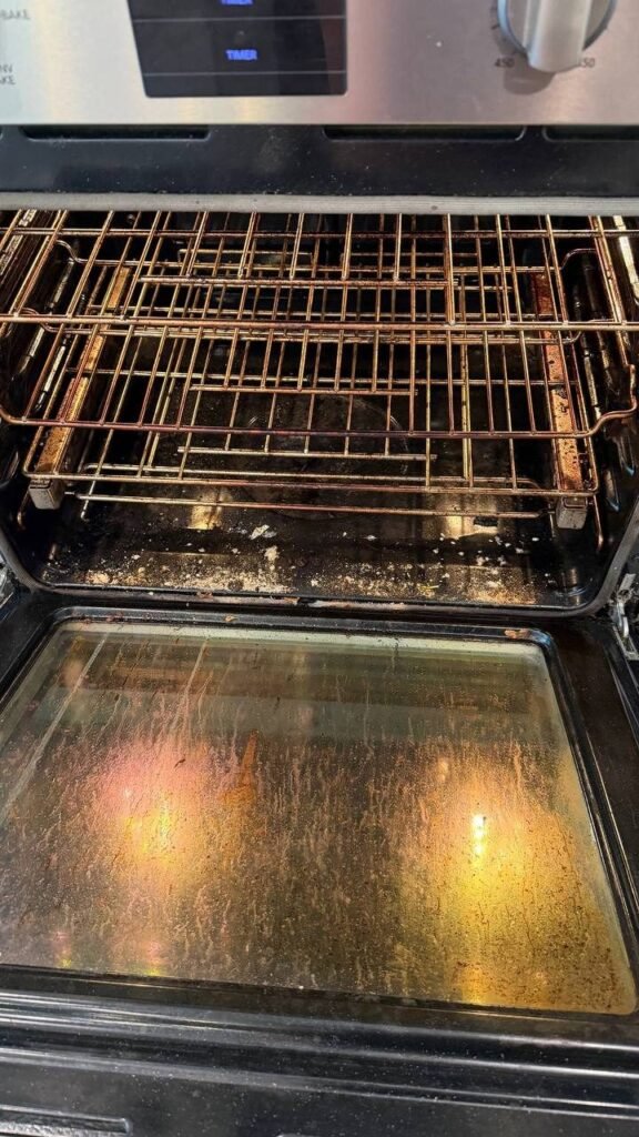 Oven interior with carbon on the floor, greasy racks and streaked door glass before JenyClean detailed cleaning in Seattle, WA