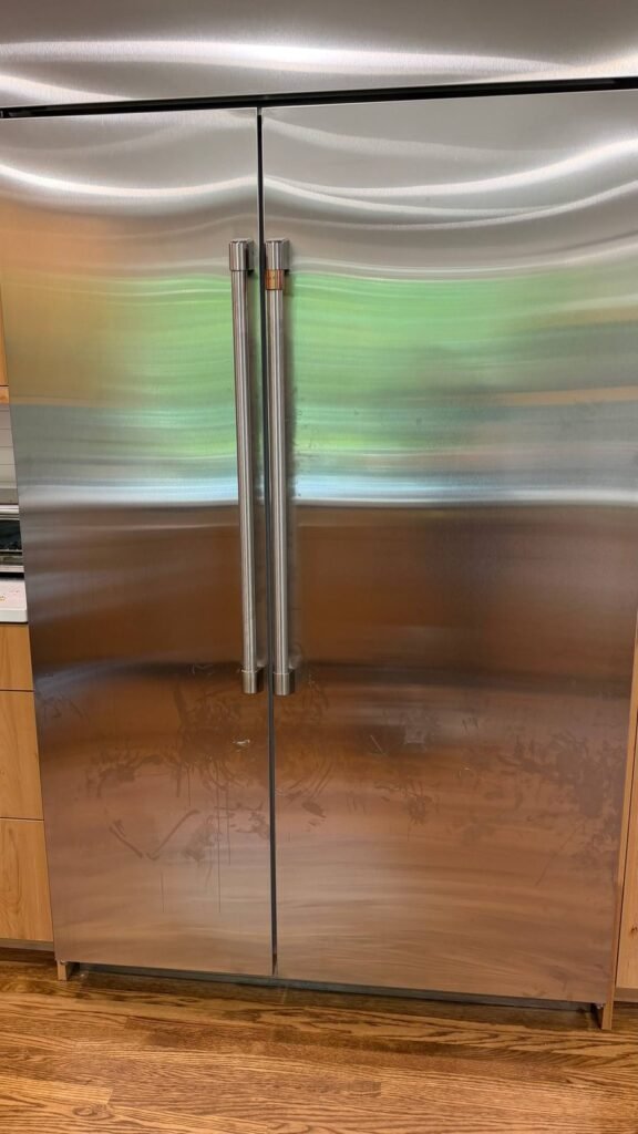Built-in stainless refrigerator with handprints and smudges on the lower doors before JenyClean regular cleaning in Seattle, WA
