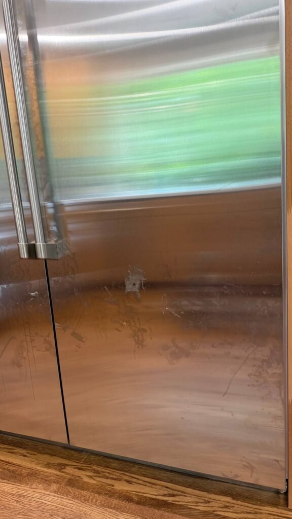 Close view of fingerprints and wipe marks on the lower stainless fridge door before JenyClean regular cleaning in Seattle, WA