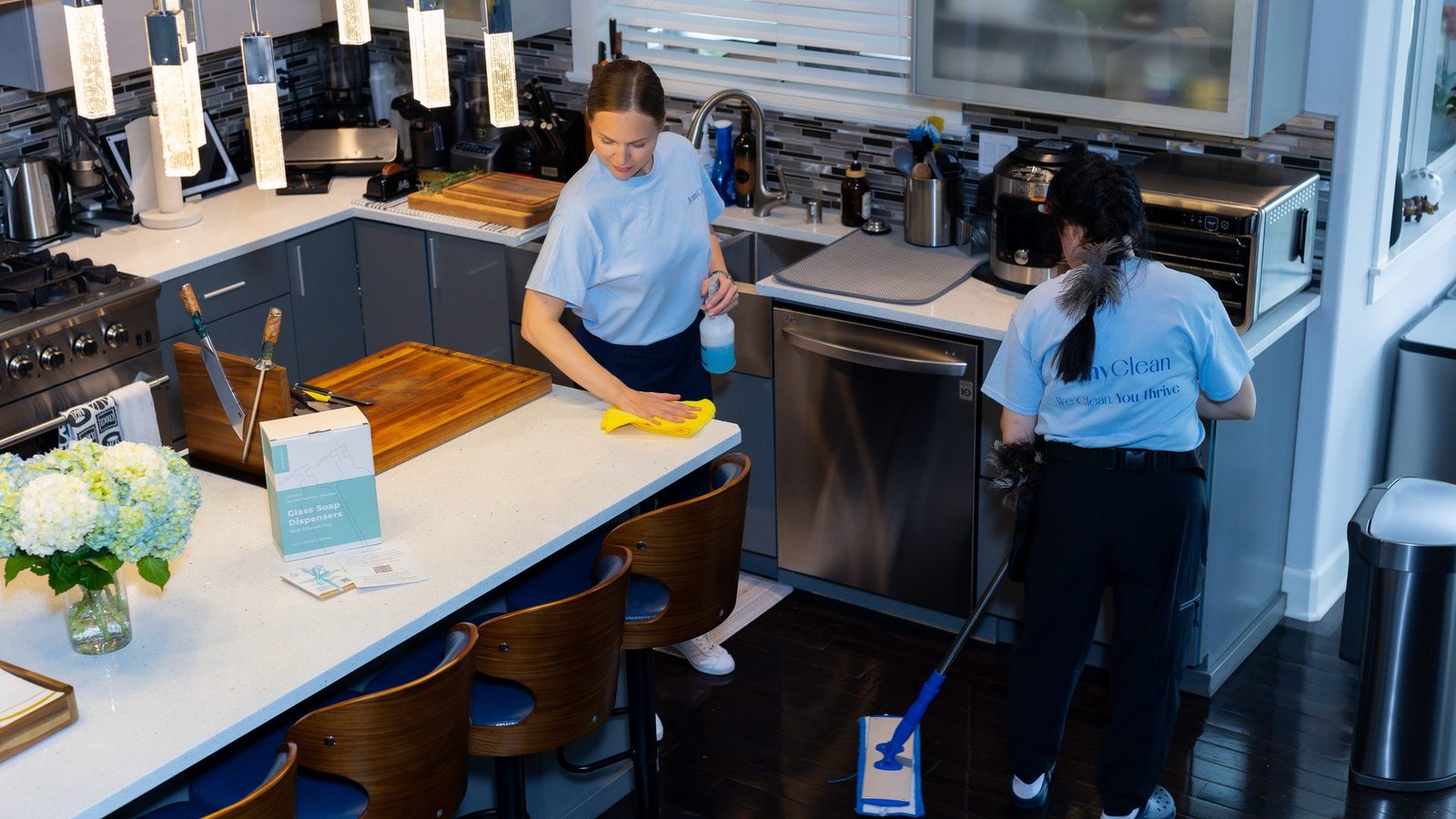 Two JenyClean cleaners wiping a kitchen island and mopping the floor