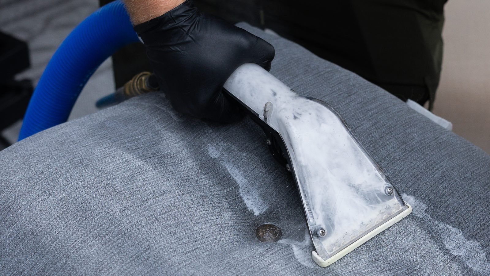 Extraction tool removing a spot from a gray fabric cushion