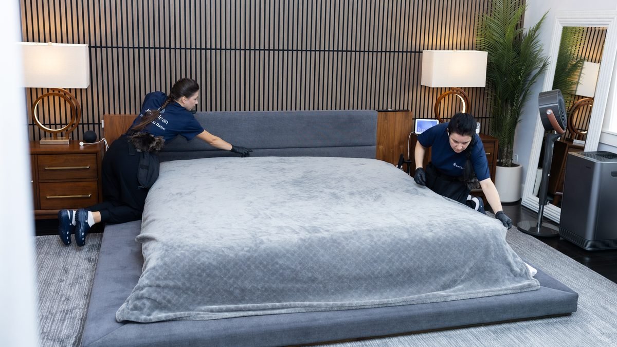 Two JenyClean cleaners making a bed in a bedroom