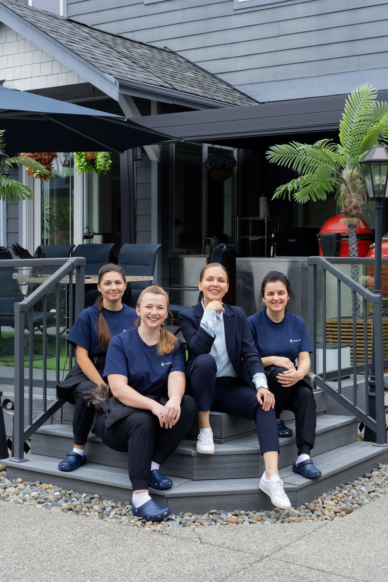 JenyClean team members seated on deck steps