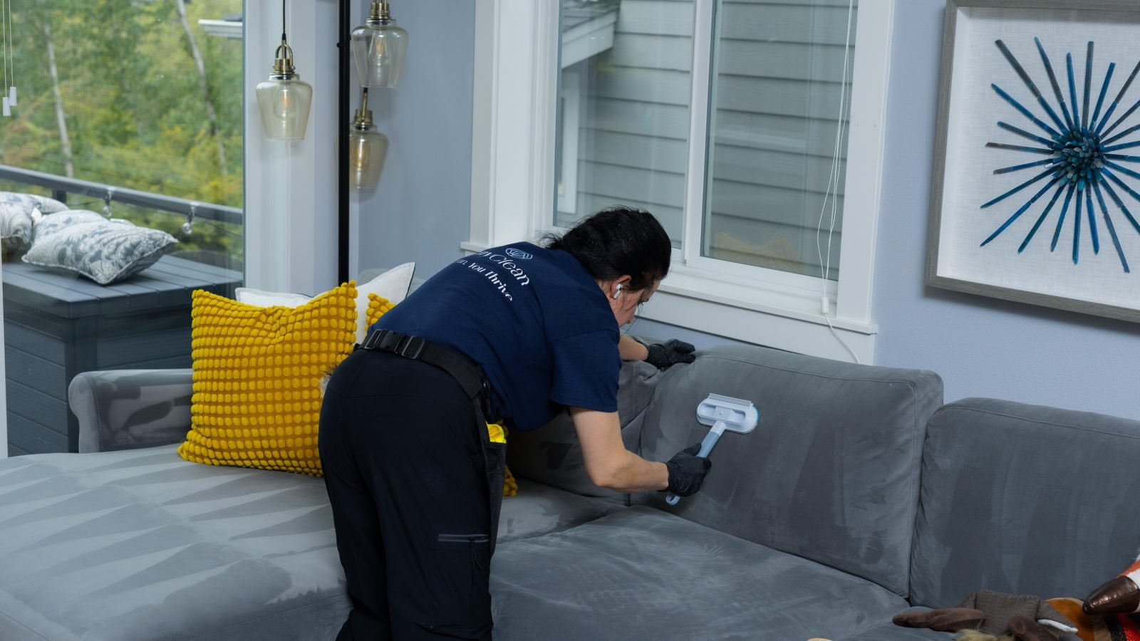 JenyClean cleaner cleaning a gray fabric sofa with a handheld upholstery tool