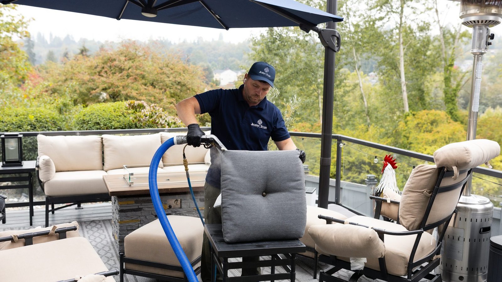 JenyClean technician cleaning an outdoor sofa cushion with an extraction wand on a deck