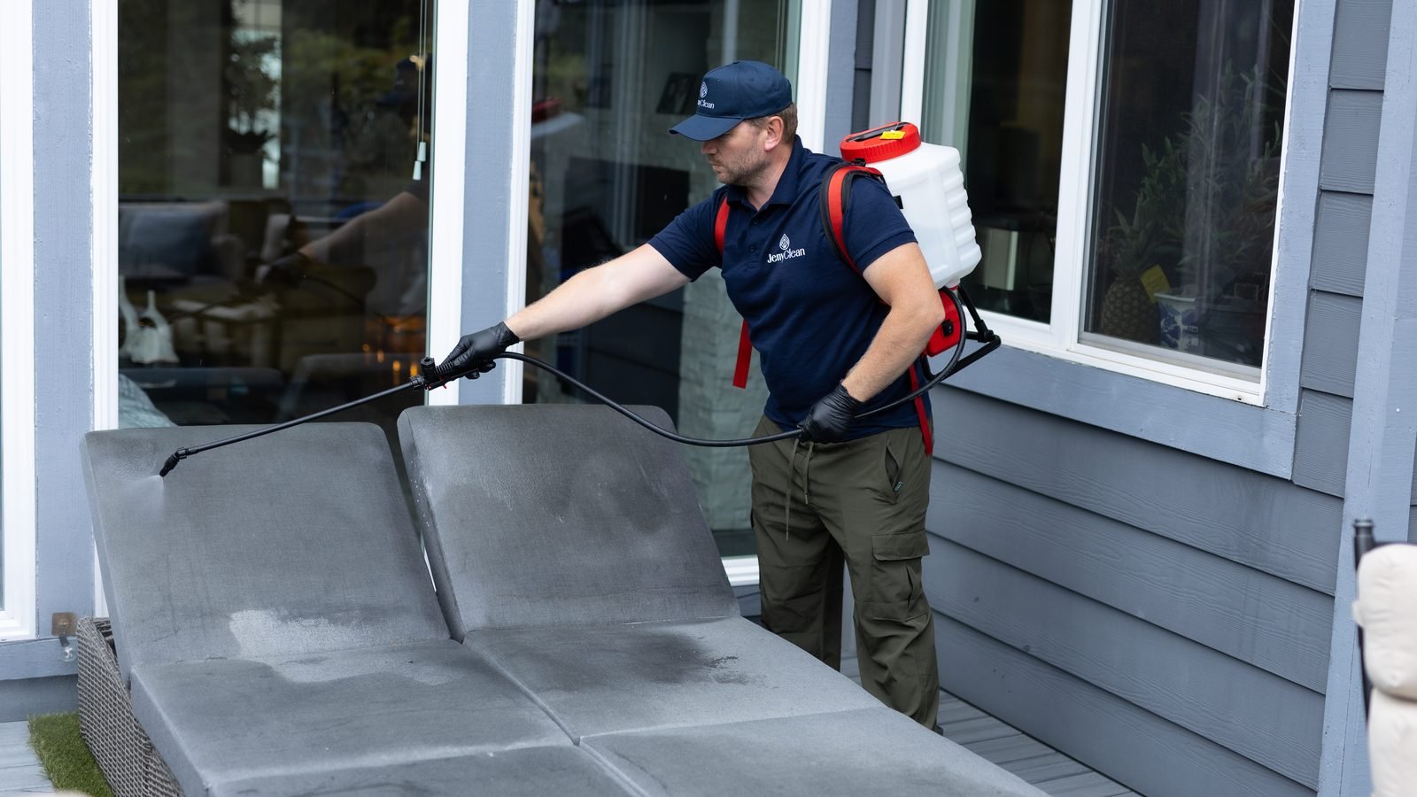 JenyClean technician pre-spraying a fabric outdoor chaise before extraction